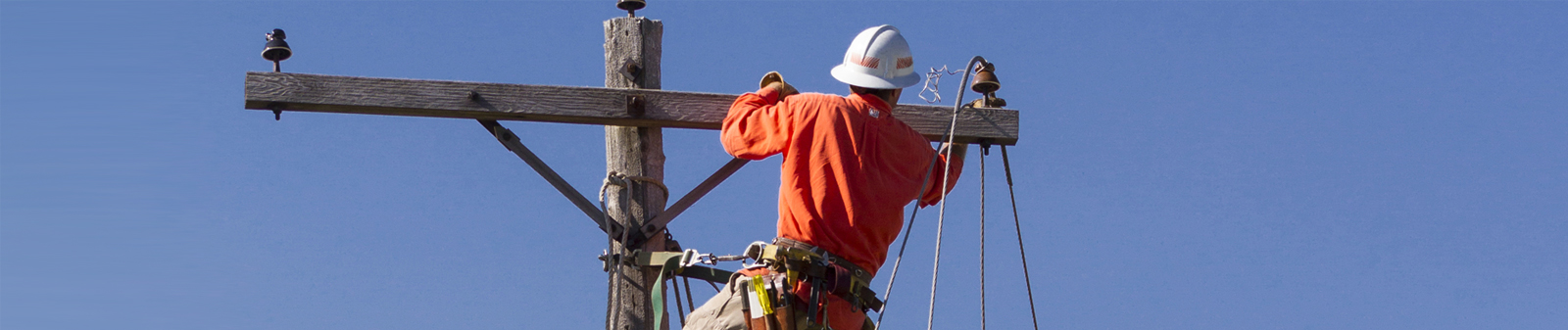 lineman at top of pole working on utility lines